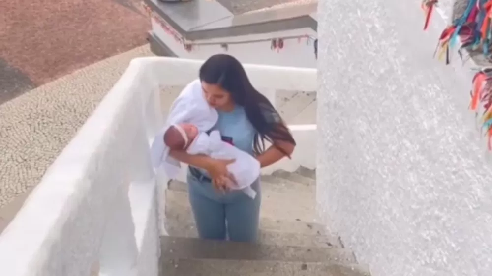 Mãe sobe escadas de joelhos com bebê no colo em promessa pela saúde da filha